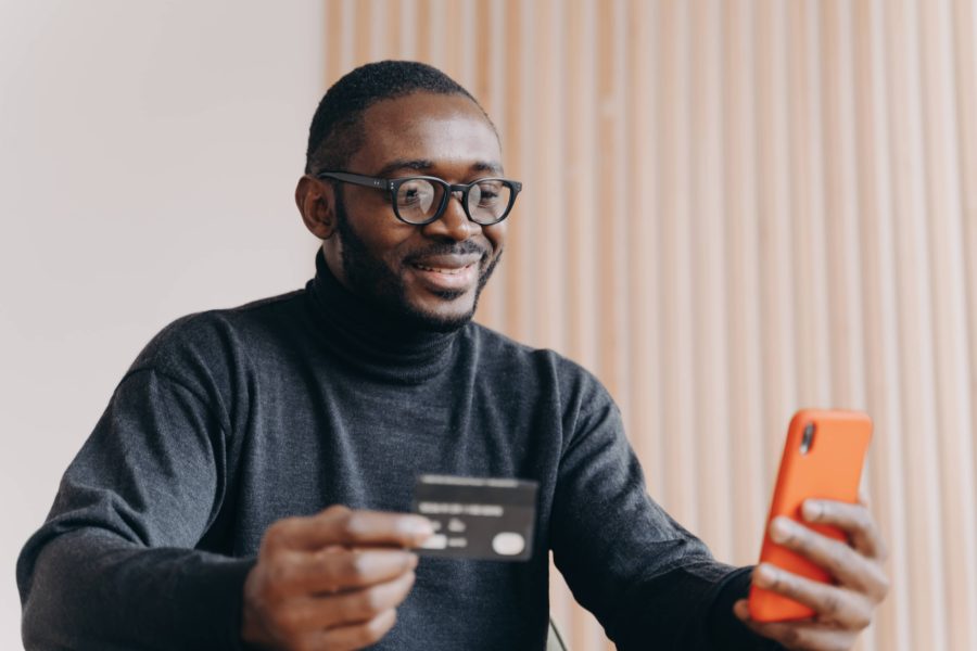 A man holding a credit card and using an app to make an online purchase.