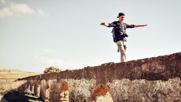 A man balanced on a wall as he thinks about balancing on unstable income.