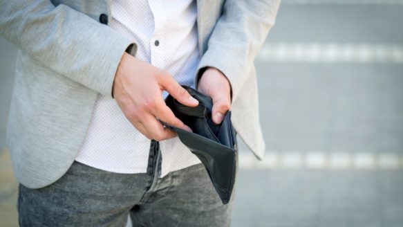A man looks in his empty wallet.