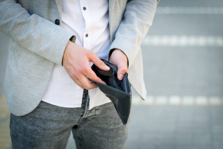 A man looks in his empty wallet.