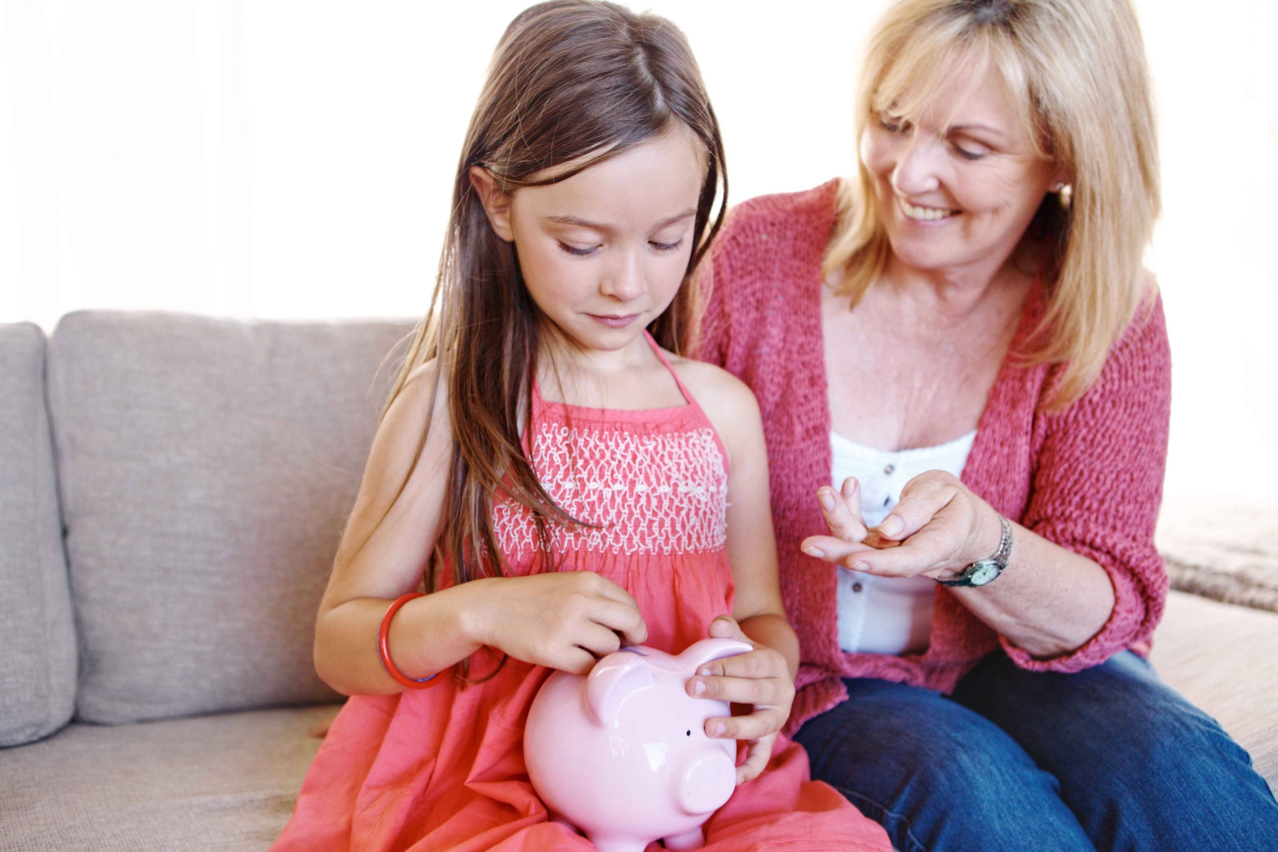 A mother teaches her child about needs vs wants and budgeting for school with a piggy bank.