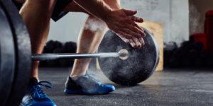 A man reaches down to pick up some weights.