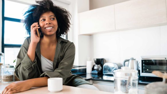 Woman on phone happy about her condo purchase since finishing her debt repayment plan