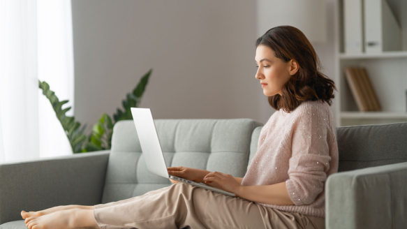 A woman reads the Money Mentors FAQs on her laptop.