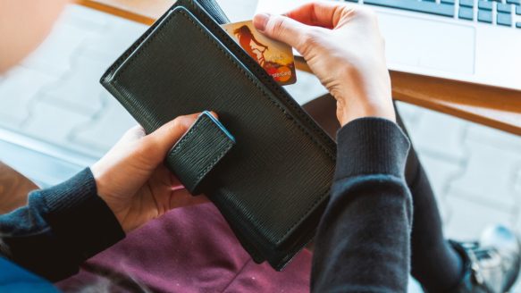 A woman reaches into her purse for her credit card.