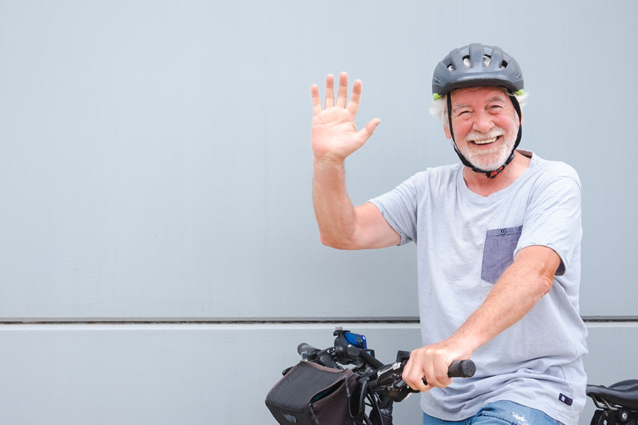 A senior man smiles and waves at the camera after taking the Money Mentors OPD program.