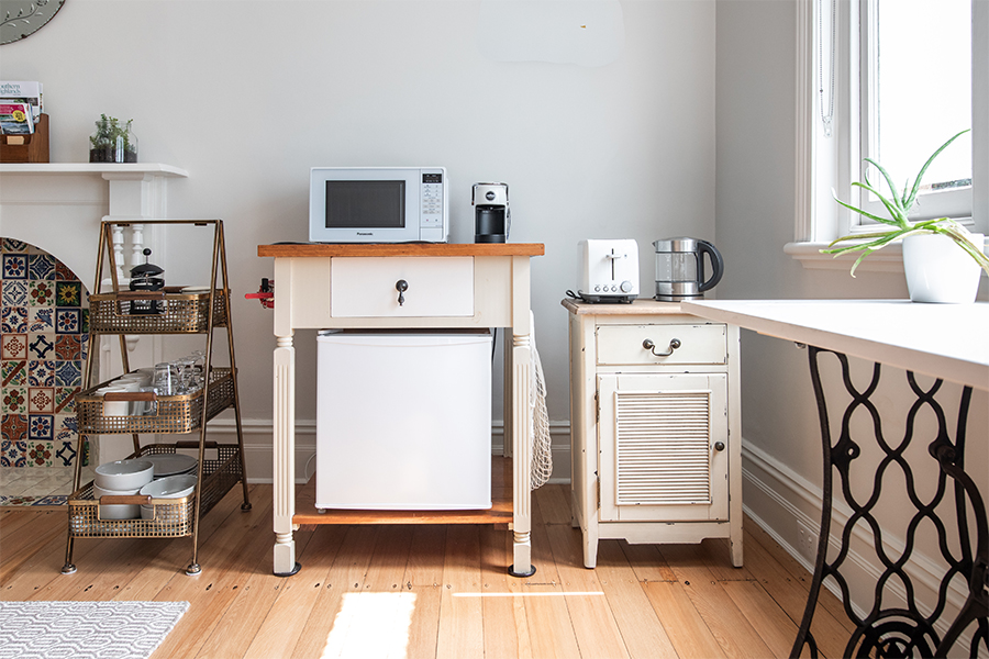 A cozy kitchen setup with a microwave, coffee maker, and mini fridge; save money on appliances with tips from Money Mentors.