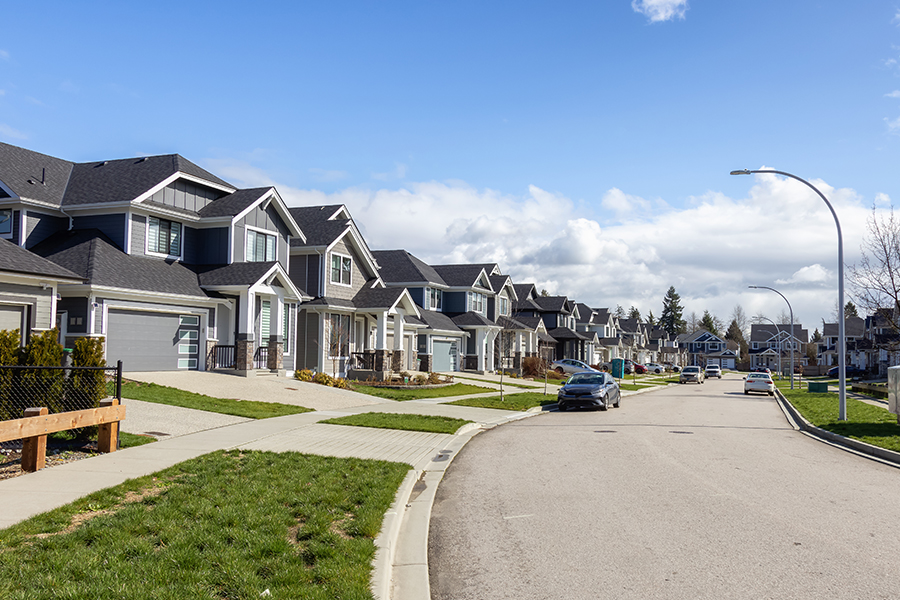 A suburban street lined with houses; save money on housing costs with budgeting strategies from Money Mentors.