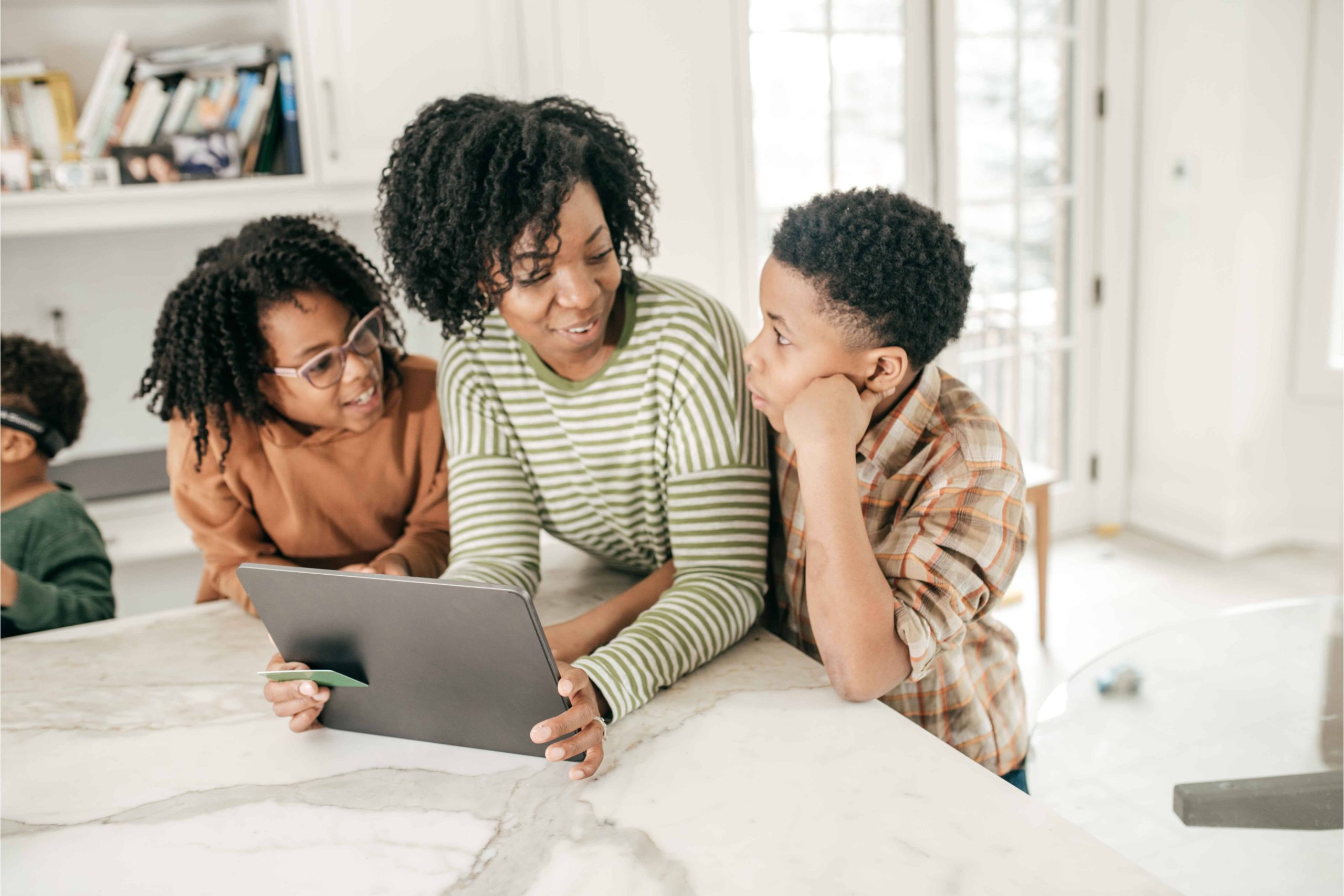 A mother and her two children look up Money Mentors financial education on an iPad.