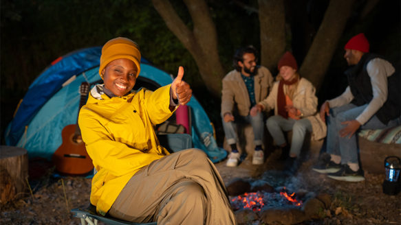 Group of friends enjoying an affordable camping staycation in Alberta, smiling around a campfire at night