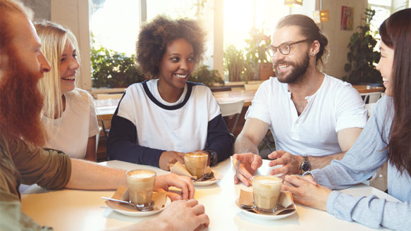 A diverse group of small business owners sharing coffee and conversation in a bright café, representing connection, community, and work-life balance.
