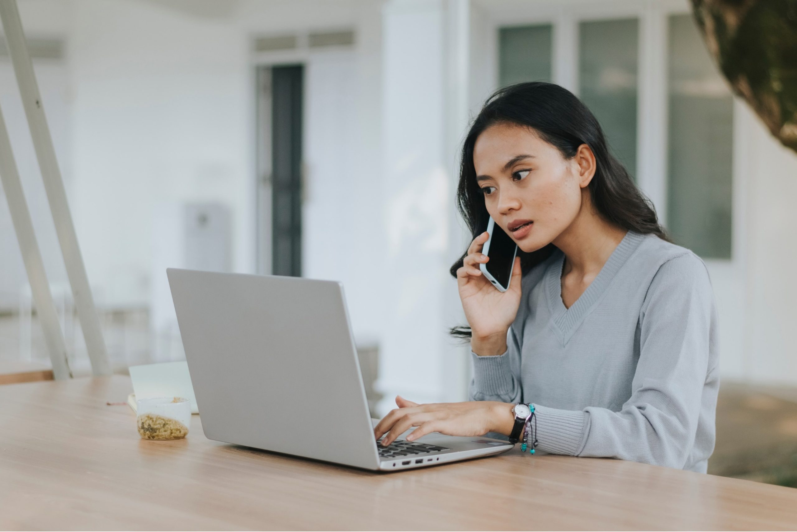 A young woman on a phone call while using a laptop, illustrating the process of negotiating a debt repayment plan