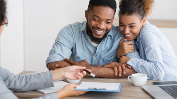 A happy young couple meet with a debt counsellor for one-on-one money coaching