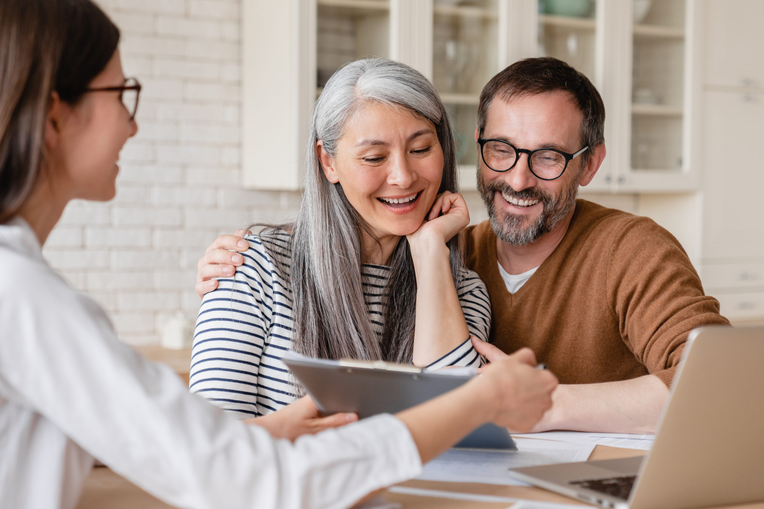 A smiling middle-aged couple consulting a credit counsellor for debt management and budgeting solutions in Alberta.