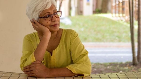 Elderly woman thoughtfully considering her retirement planning and debt-free future, highlighting the financial guidance and support from Money Mentors.